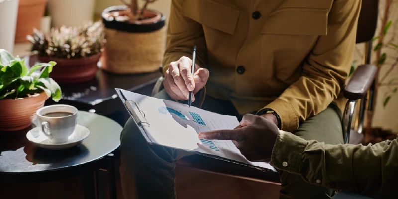 Dos personas revisan un informe con gráficos, analizando datos en un entorno de trabajo colaborativo