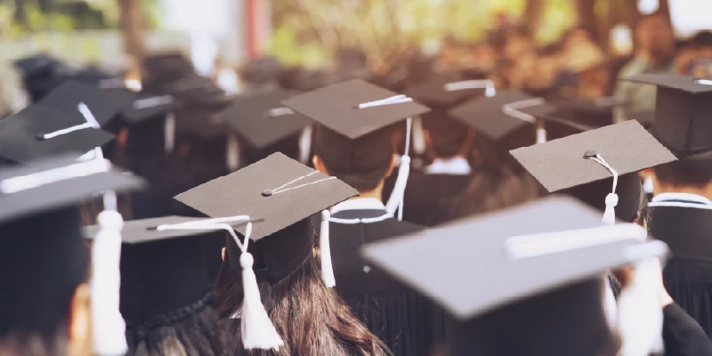 Personas de espaldas, con toga y birrete, en su ceremonia de graduación.