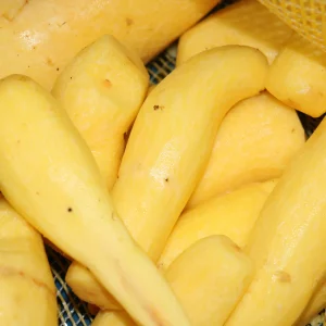 Arracachas frescas amarillas sin piel, recién cosechadas, apiladas para su venta en mercado local.